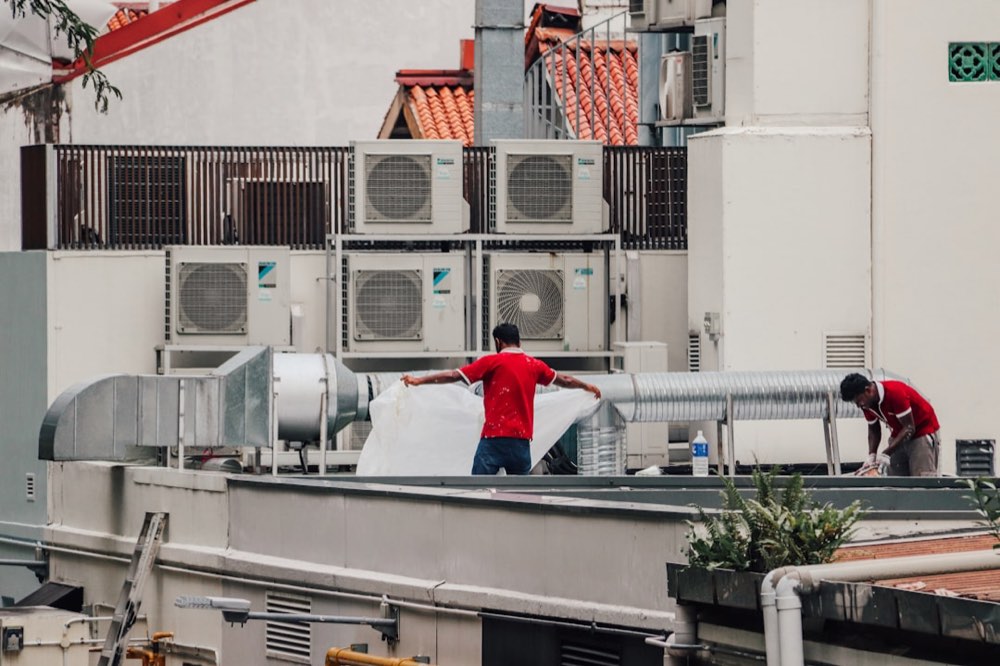 HVAC technicians working on rooftop ductwork and condenser units during a commercial job